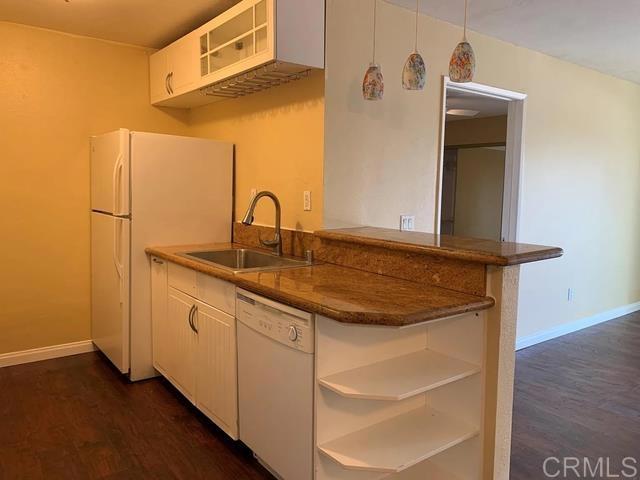 kitchen featuring sink, decorative light fixtures, kitchen peninsula, white appliances, and white cabinets