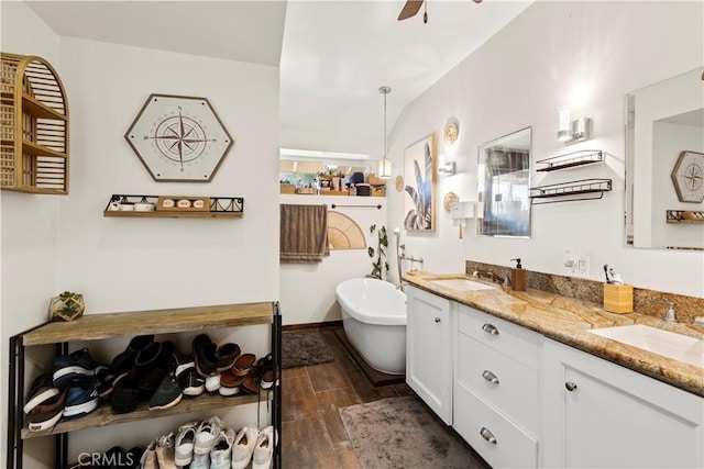 bathroom featuring double vanity, a freestanding tub, wood finish floors, and a sink