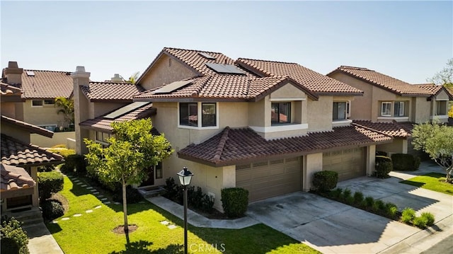 mediterranean / spanish-style home featuring concrete driveway, an attached garage, roof mounted solar panels, a front lawn, and stucco siding