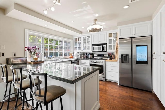 kitchen featuring a peninsula, appliances with stainless steel finishes, white cabinets, and a sink