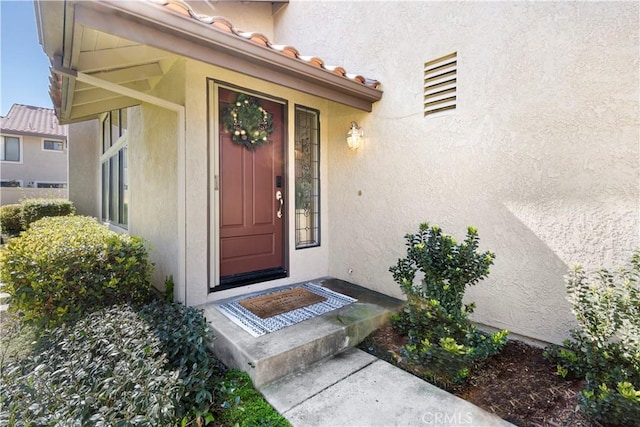 property entrance with a tiled roof and stucco siding