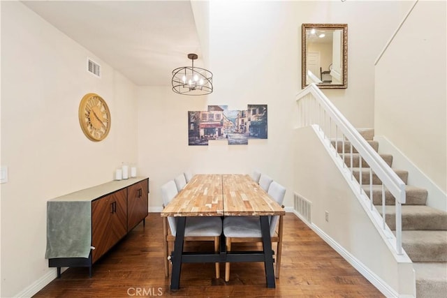 dining area featuring dark wood-type flooring, stairway, visible vents, and an inviting chandelier