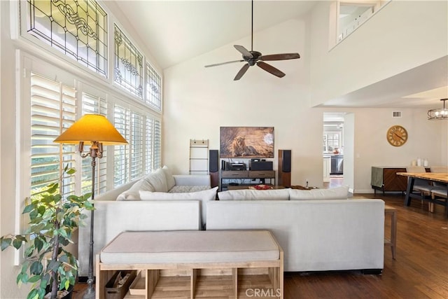 living area featuring high vaulted ceiling, visible vents, dark wood finished floors, and ceiling fan with notable chandelier