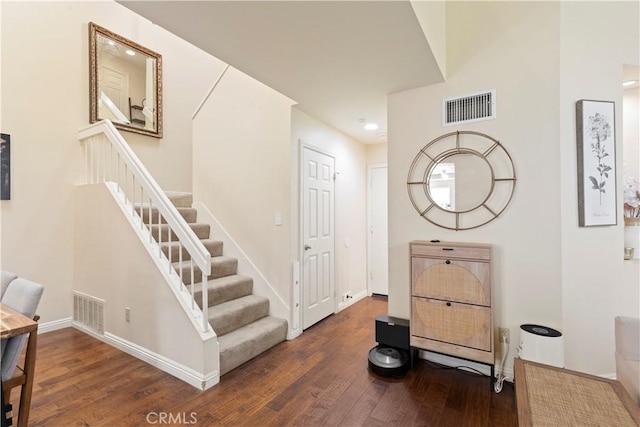 interior space with stairs, visible vents, baseboards, and wood finished floors