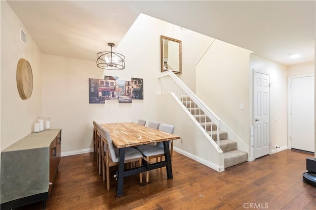 dining space featuring dark wood finished floors, a notable chandelier, visible vents, baseboards, and stairs