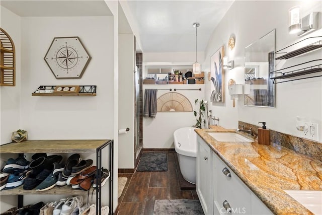 bathroom featuring wood finish floors, double vanity, a soaking tub, a stall shower, and a sink