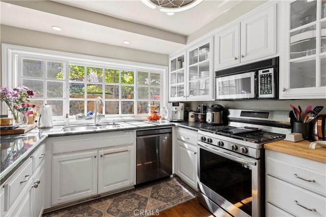 kitchen featuring glass insert cabinets, white cabinetry, stainless steel appliances, and a sink