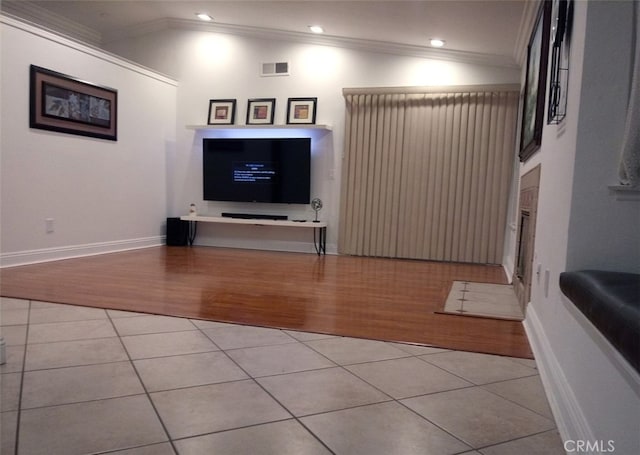 living area with light tile patterned floors, visible vents, and crown molding