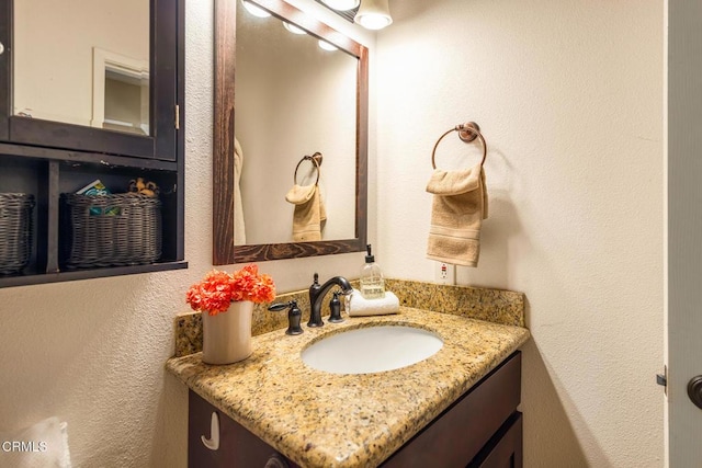 bathroom with a textured wall and vanity