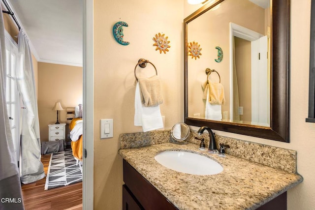 bathroom featuring vanity, wood finished floors, crown molding, and ensuite bathroom