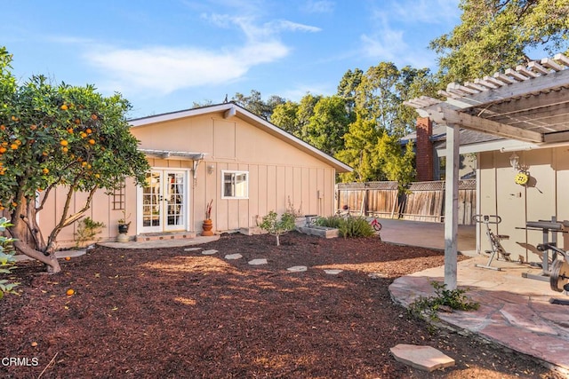 exterior space with a pergola, fence, french doors, a patio area, and board and batten siding