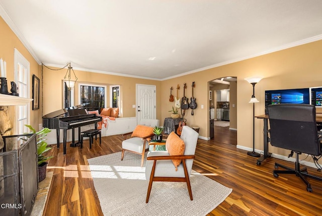 living area featuring ornamental molding, arched walkways, dark wood-style flooring, and baseboards