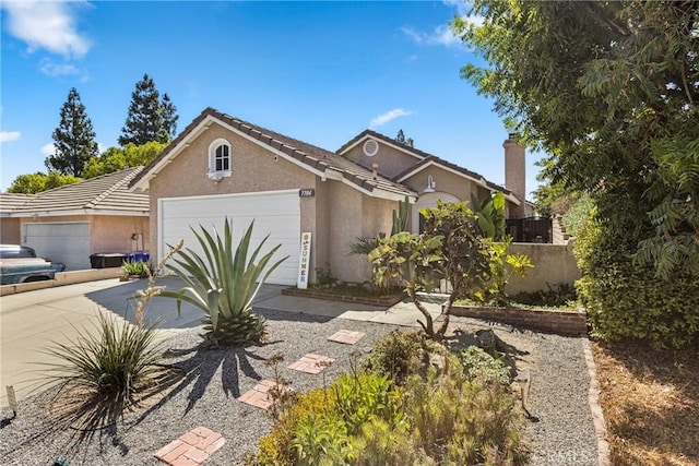 view of front facade with a tile roof, stucco siding, fence, a garage, and driveway