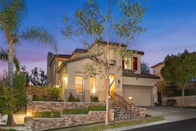 mediterranean / spanish home with stucco siding, an attached garage, a chimney, and driveway