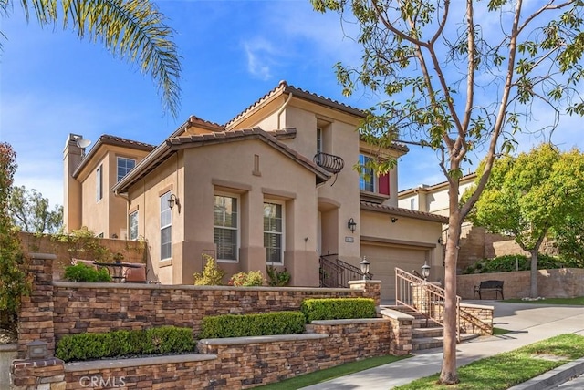 mediterranean / spanish-style house featuring fence, concrete driveway, stucco siding, a chimney, and a garage