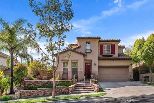 mediterranean / spanish home with stucco siding, driveway, a gate, a tile roof, and an attached garage