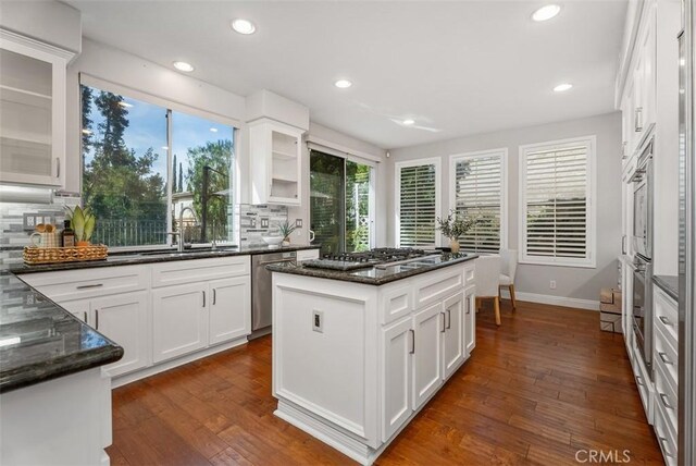 kitchen featuring dark wood-style floors, white cabinetry, appliances with stainless steel finishes, and dark stone counters