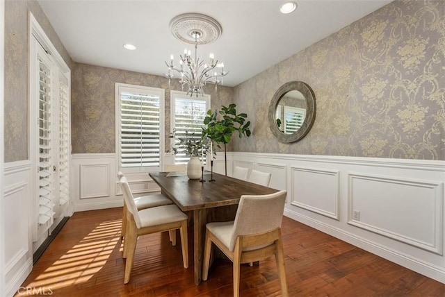 dining room with an inviting chandelier, dark wood-style floors, wainscoting, and wallpapered walls