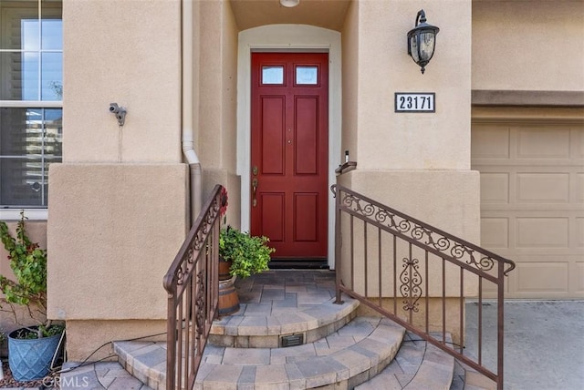 property entrance featuring a garage and stucco siding