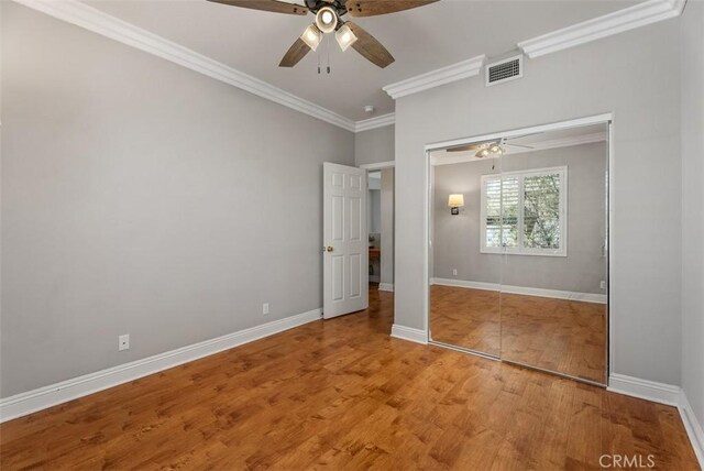 unfurnished bedroom with visible vents, ornamental molding, baseboards, and wood finished floors