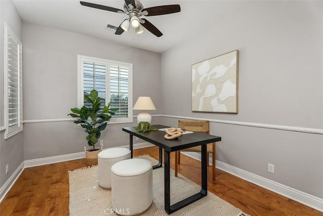 office area with a ceiling fan, wood finished floors, visible vents, and baseboards