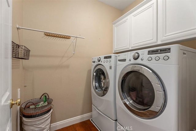 laundry area featuring washer and dryer, baseboards, cabinet space, and dark wood finished floors