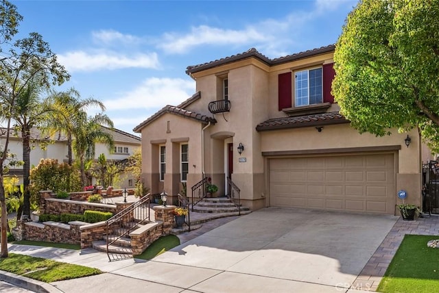 mediterranean / spanish house with a tile roof, stucco siding, concrete driveway, and a garage