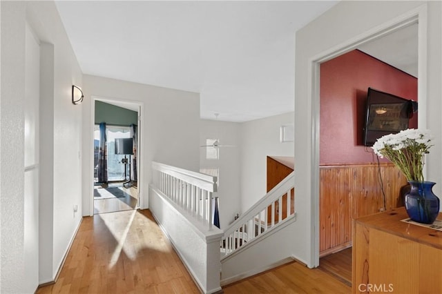 hallway with wood finished floors, an upstairs landing, and baseboards