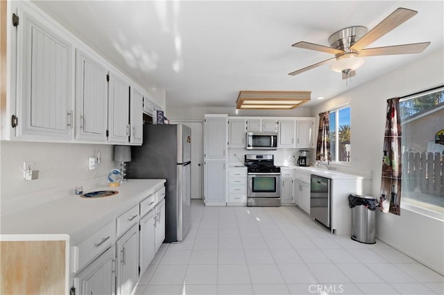 kitchen featuring appliances with stainless steel finishes, white cabinets, light countertops, and a sink