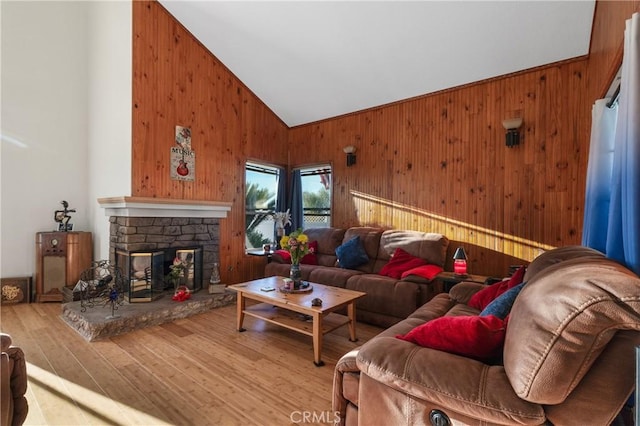 living room featuring high vaulted ceiling, a fireplace, wooden walls, and wood finished floors