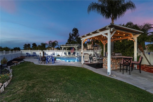 yard at dusk featuring a fenced in pool, area for grilling, a fenced backyard, outdoor dry bar, and a patio area