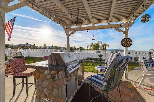 view of patio featuring area for grilling, a fenced backyard, grilling area, outdoor dry bar, and a pergola