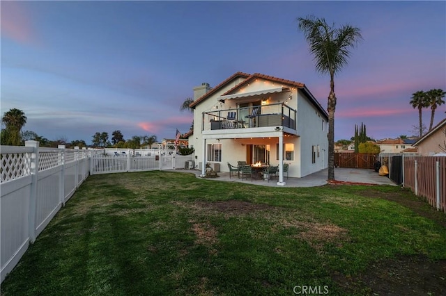 back of property featuring a lawn, a patio area, a fenced backyard, and a balcony