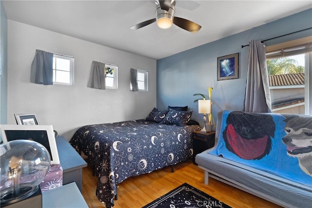 bedroom with ceiling fan, multiple windows, and wood finished floors