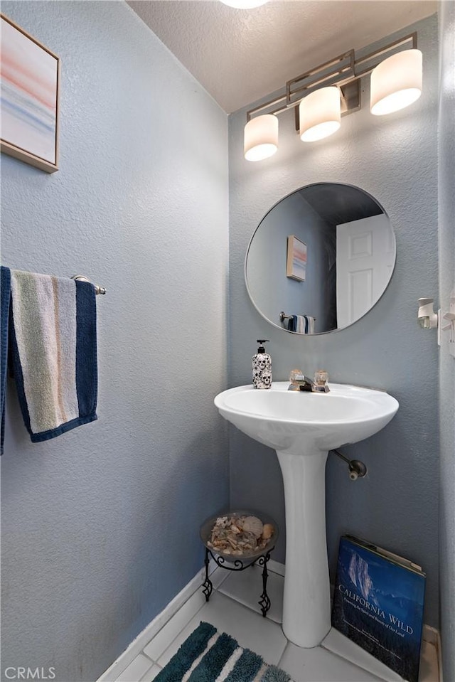 bathroom featuring tile patterned flooring, a textured wall, and a textured ceiling