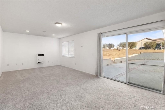 carpeted empty room featuring heating unit and a textured ceiling