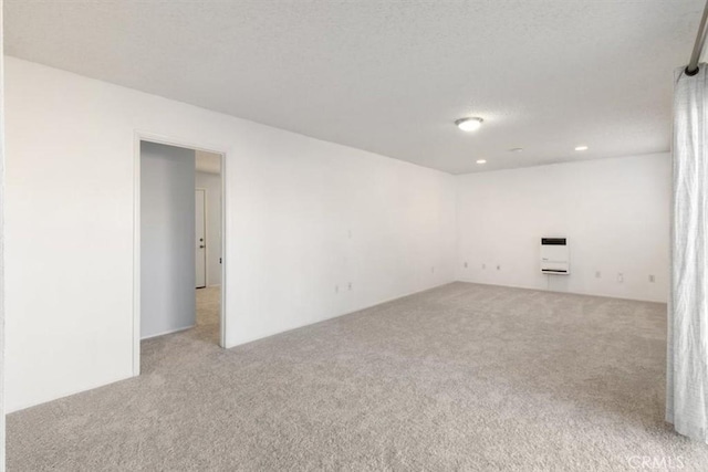 spare room featuring heating unit and light colored carpet