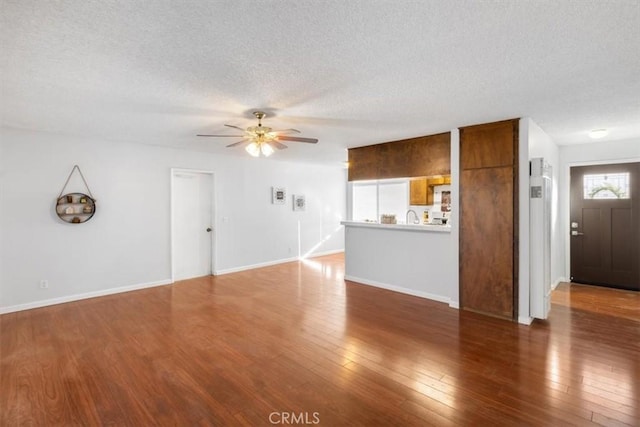 unfurnished living room with ceiling fan, dark wood-type flooring, and a textured ceiling