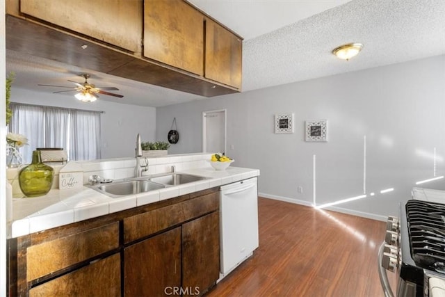 kitchen featuring sink, tile countertops, a textured ceiling, dark hardwood / wood-style flooring, and dishwasher