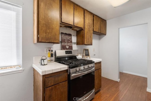 kitchen featuring tile countertops, gas stove, and light wood-type flooring