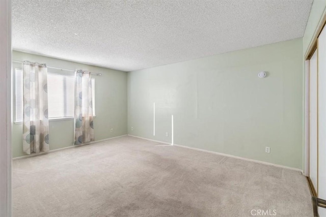 spare room with light colored carpet and a textured ceiling