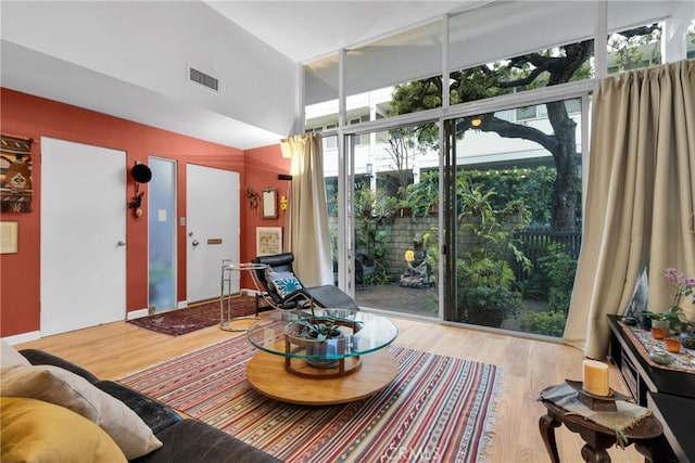 sitting room with expansive windows, light hardwood / wood-style floors, and a high ceiling