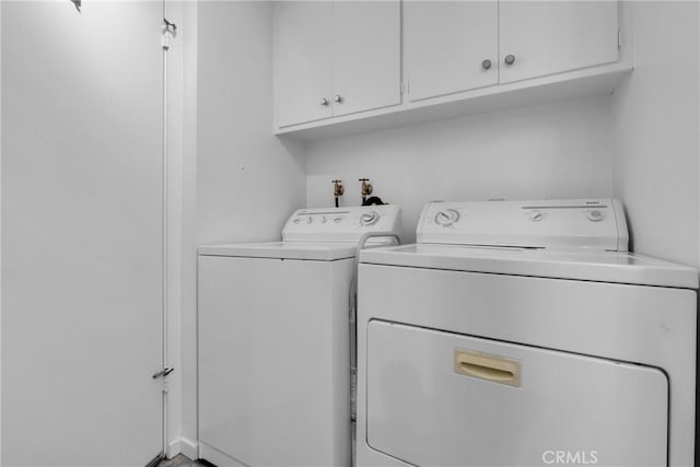 clothes washing area featuring cabinets and washing machine and clothes dryer