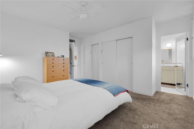 bedroom with ceiling fan, ensuite bathroom, carpet, and two closets