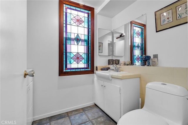 bathroom featuring vanity, toilet, and tile walls