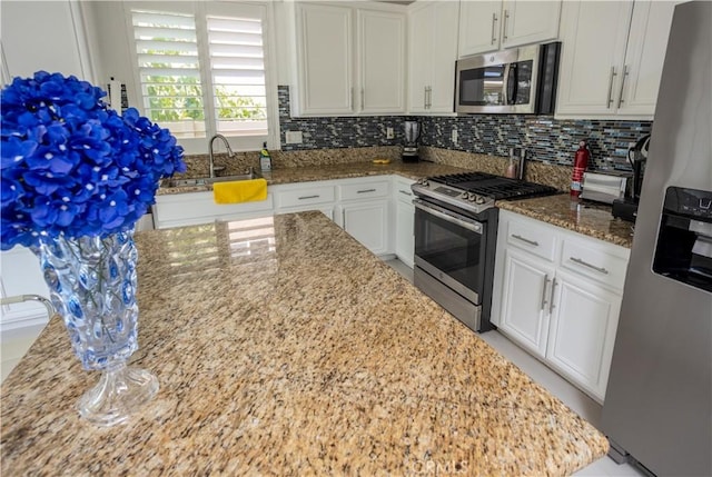 kitchen featuring appliances with stainless steel finishes, white cabinetry, and light stone counters