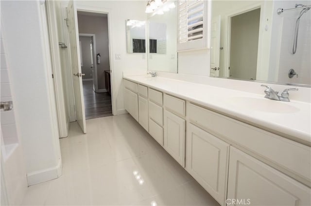 full bath featuring tile patterned flooring, a sink, baseboards, and double vanity