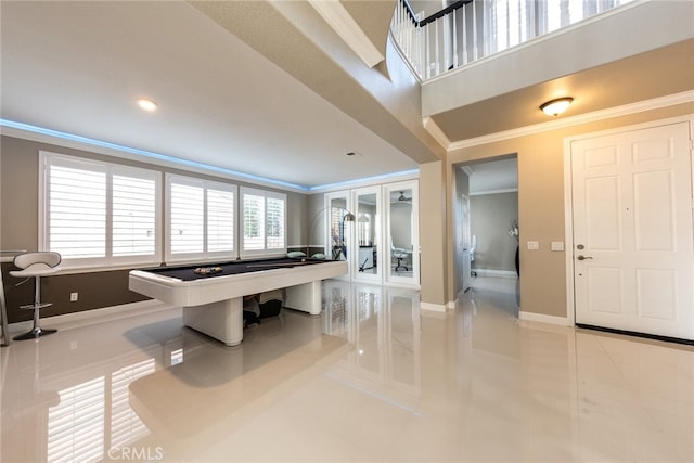 interior space with tile patterned flooring, crown molding, a high ceiling, and baseboards