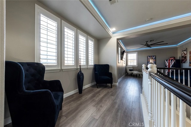living area featuring wood finished floors, visible vents, crown molding, a ceiling fan, and a raised ceiling