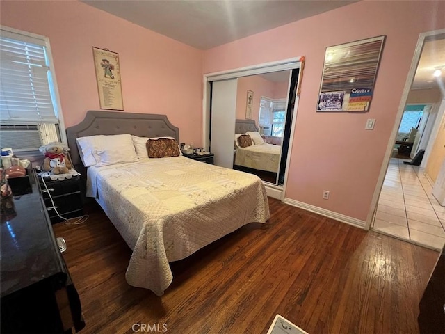 bedroom with dark wood-type flooring, a closet, and cooling unit